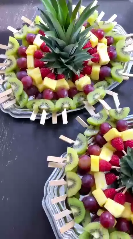 Deux couronnes de brochettes de fruits sur une table sombre
