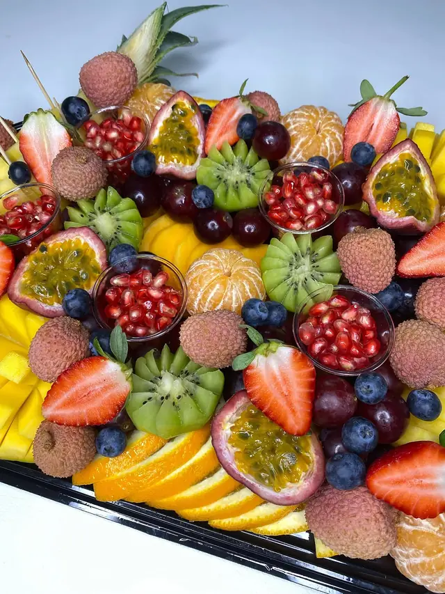 Plateau de fruits exotiques : lychees, clémentines pelées, grenade en coupelles, kiwis taillés en fleur et fruits de la passion