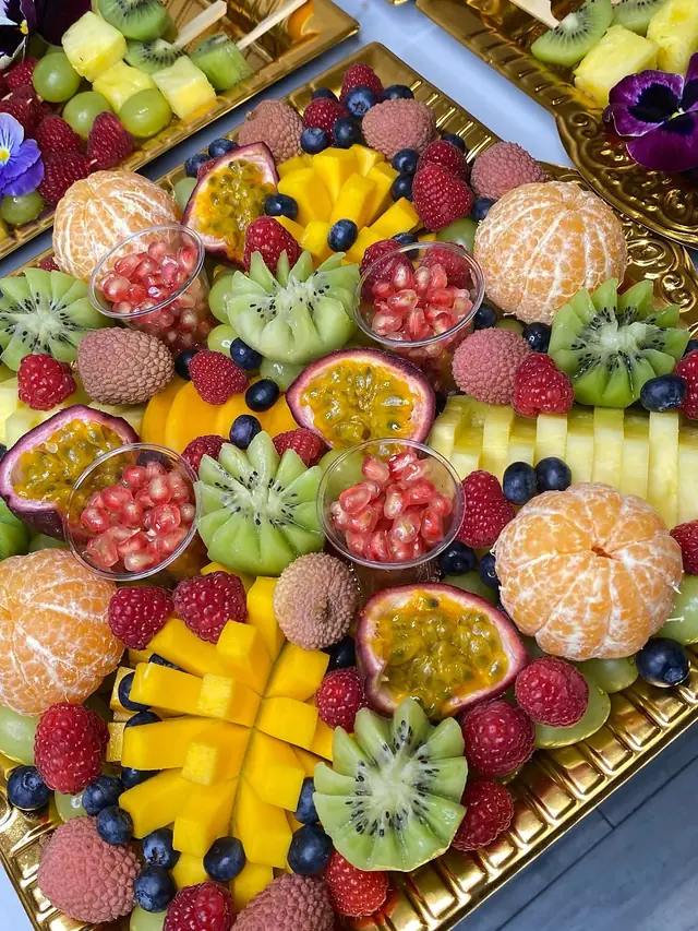 Plateau de kiwis taillés en fleur, clémentines pelées, mangue en damier, grenade et pensées