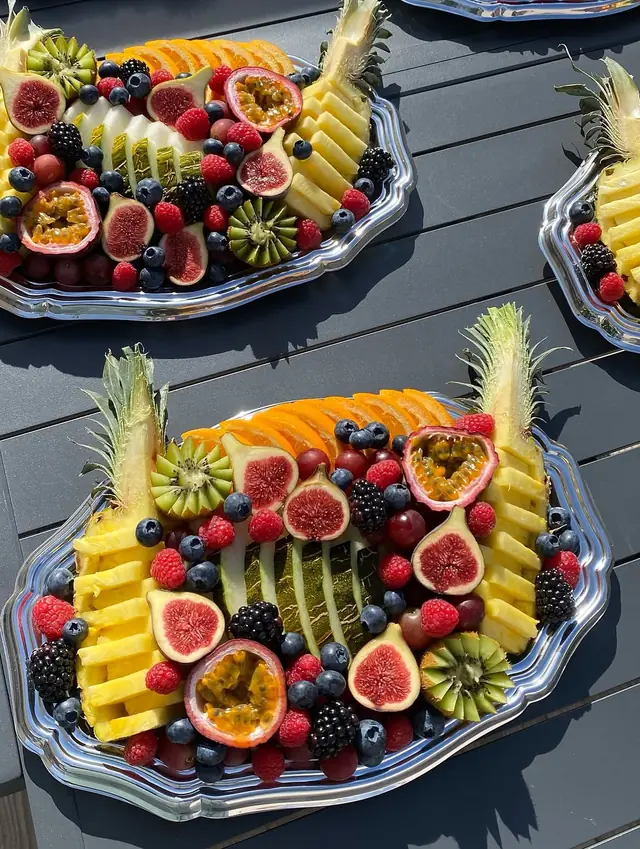 Plateaux de fruits au soleil sur une table d’extérieur : figues, melon, baies et ananas