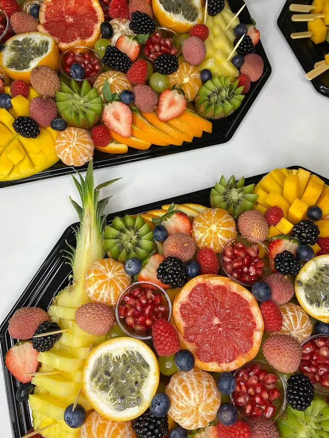 Deux plateaux vus de dessus : pamplemousse, grenadilles, clémentines, lychees et fruits rouges